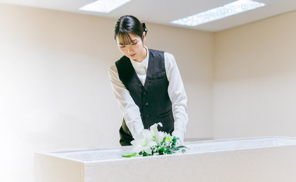 大田区葬儀相談室が白い祭壇に花を整える搬送サポートの女性スタッフ