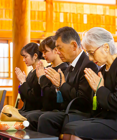 大田区葬儀相談室のスタッフと遺族が本堂で手を合わせる
