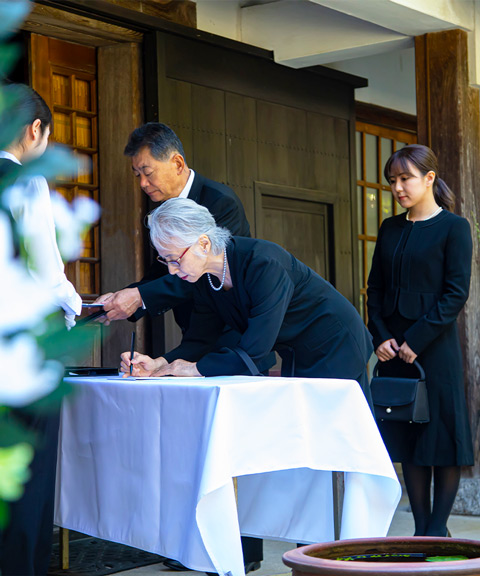 大田区葬儀相談室の受付で高齢の女性が記帳し若い女性が待つ葬儀の場面
