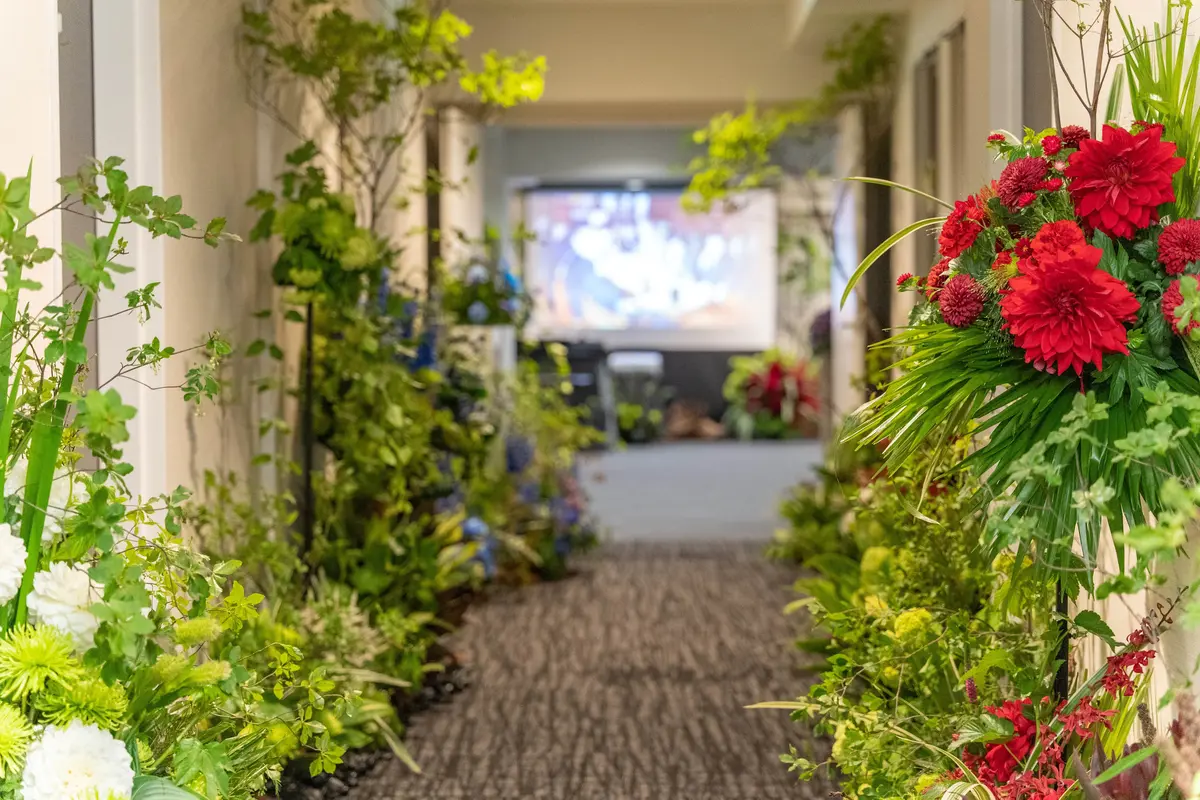 大田区葬儀相談室が花いっぱいに飾られた通路の祭壇で送る葬儀プランを案内している