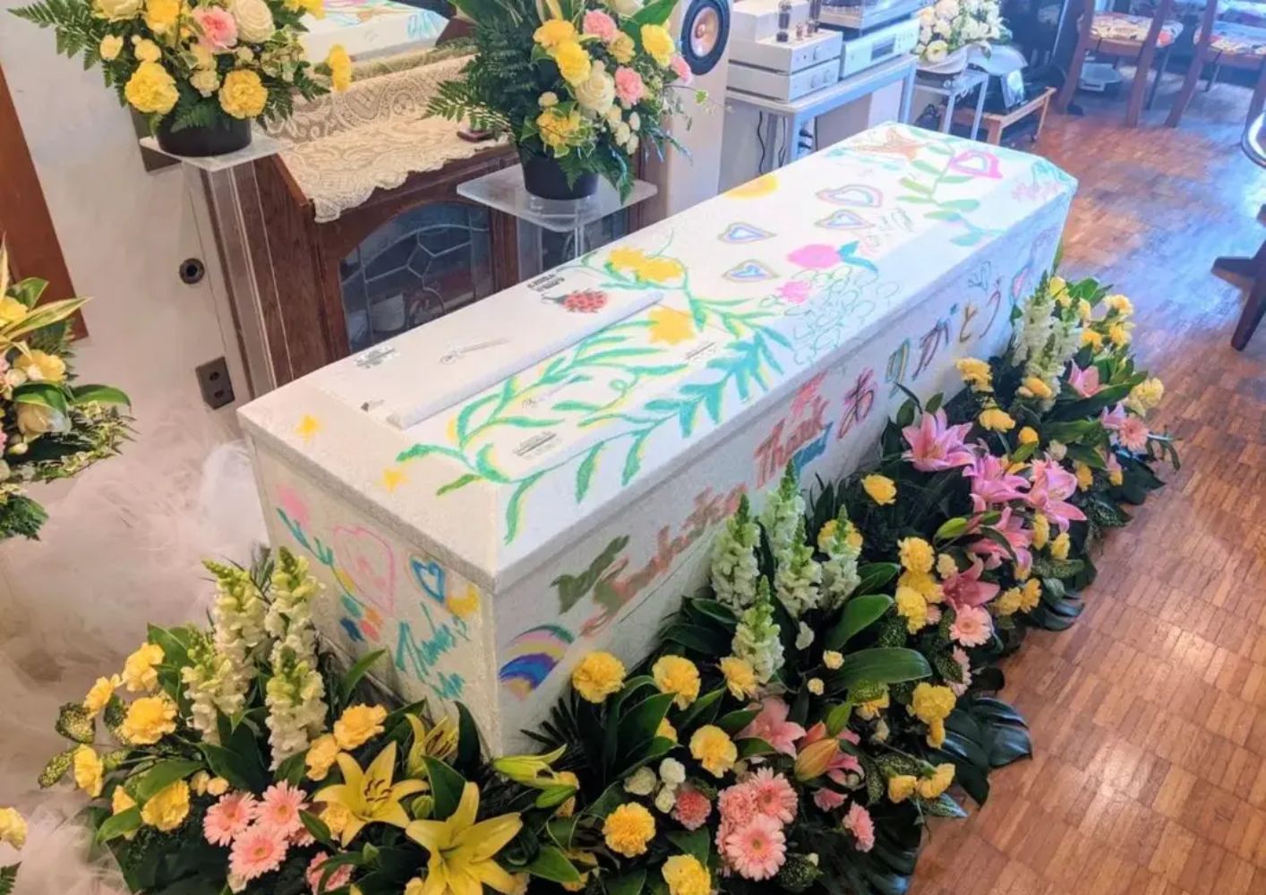 大田区葬儀相談室の飾られた花に囲まれた子どもが描いた絵入り棺が大田区 葬儀の式場に安置されている