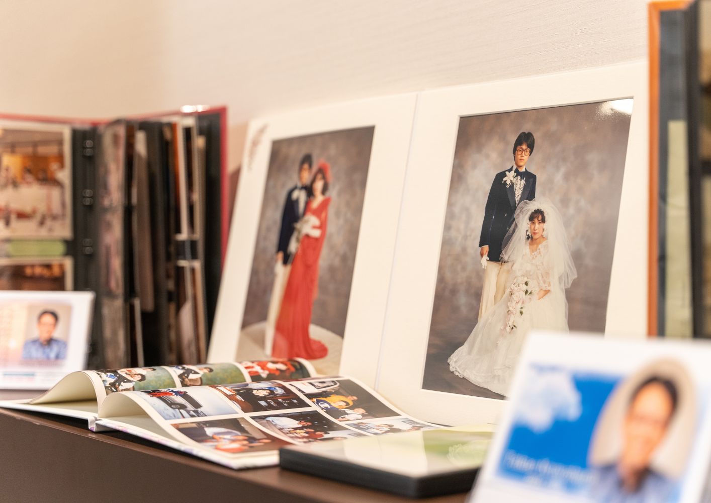 大田区葬儀相談室のご家族葬用写真ライブラリーに並ぶ白い額装の結婚写真とアルバム、大田区 葬儀の思い出保管