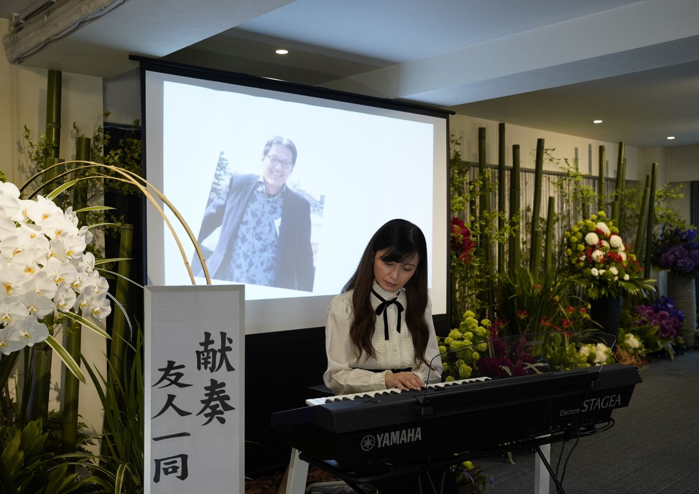 大田区葬儀相談室でピアノを弾き故人を送る女性が祭壇前で演奏している